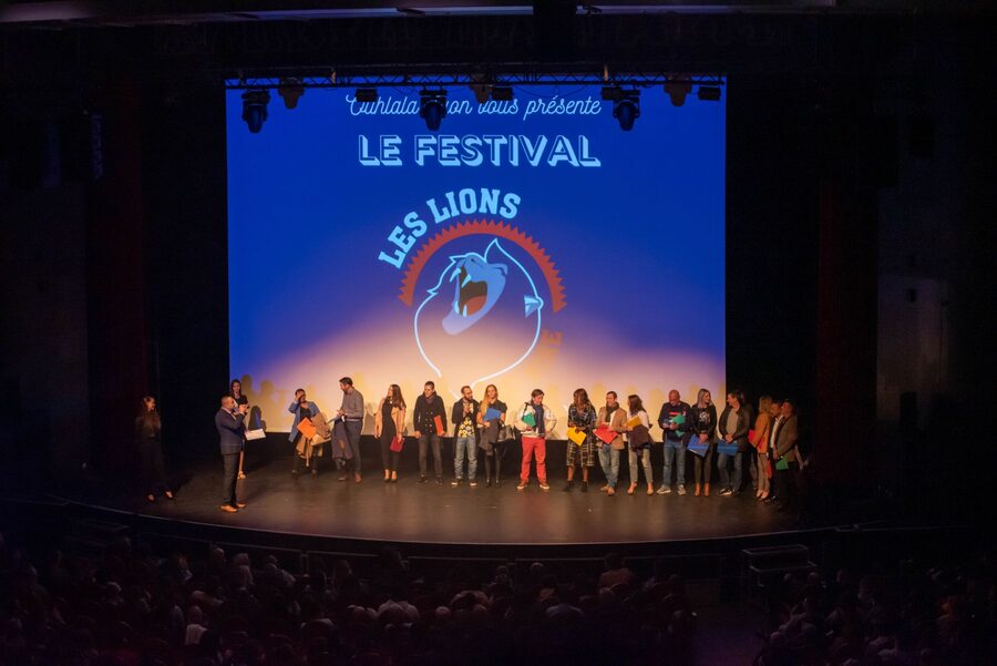 Les artistes réunis sur scène devant l'écran du festival Les Lions du Rire